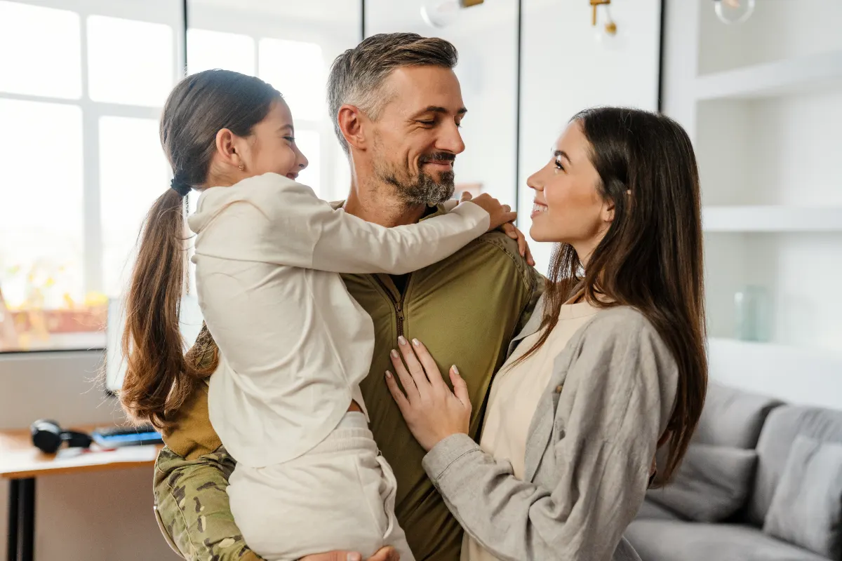 A veteran holding his young daughter while his partner looks on