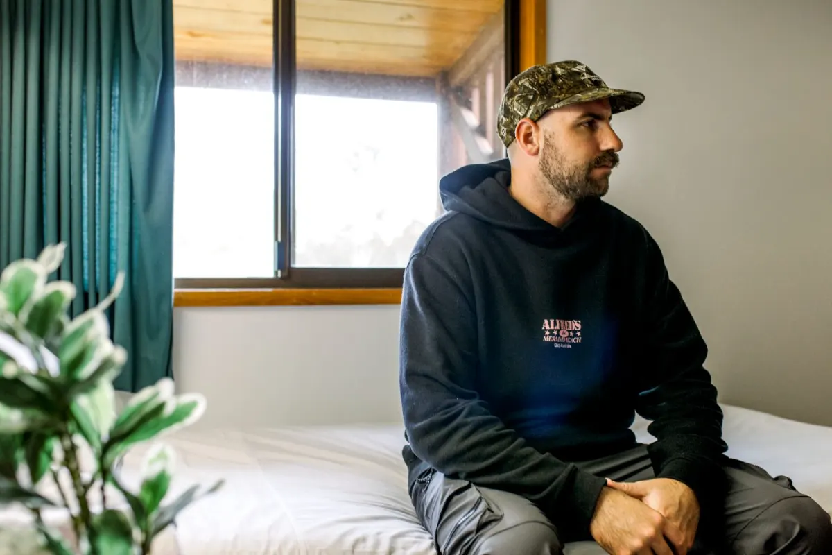 A veteran sitting on a bed by the window, taking a quiet moment